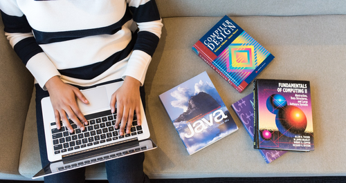 Freelancer on laptop with manuals and books next to them