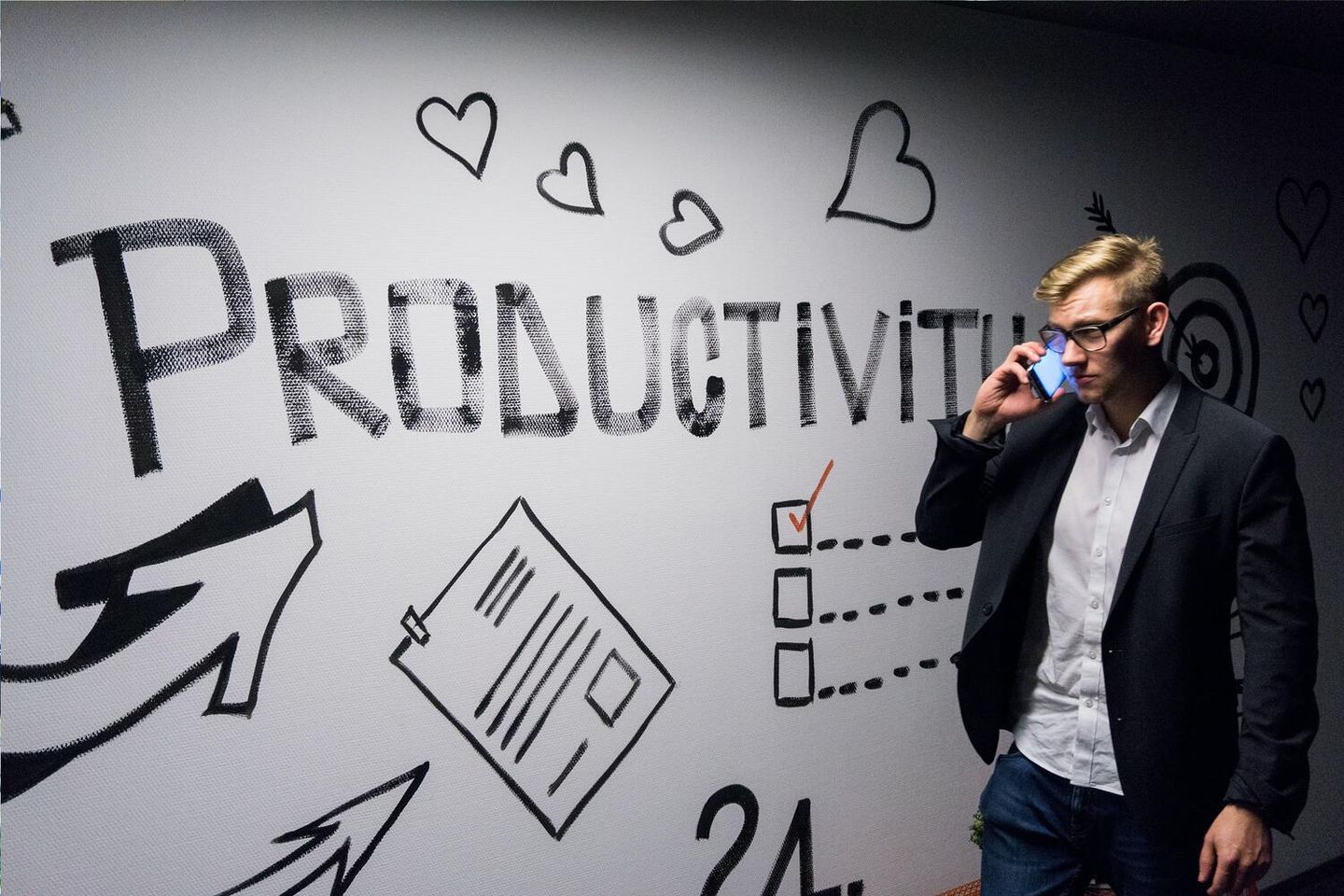 A man talks on the phone in front of a productivity sign.