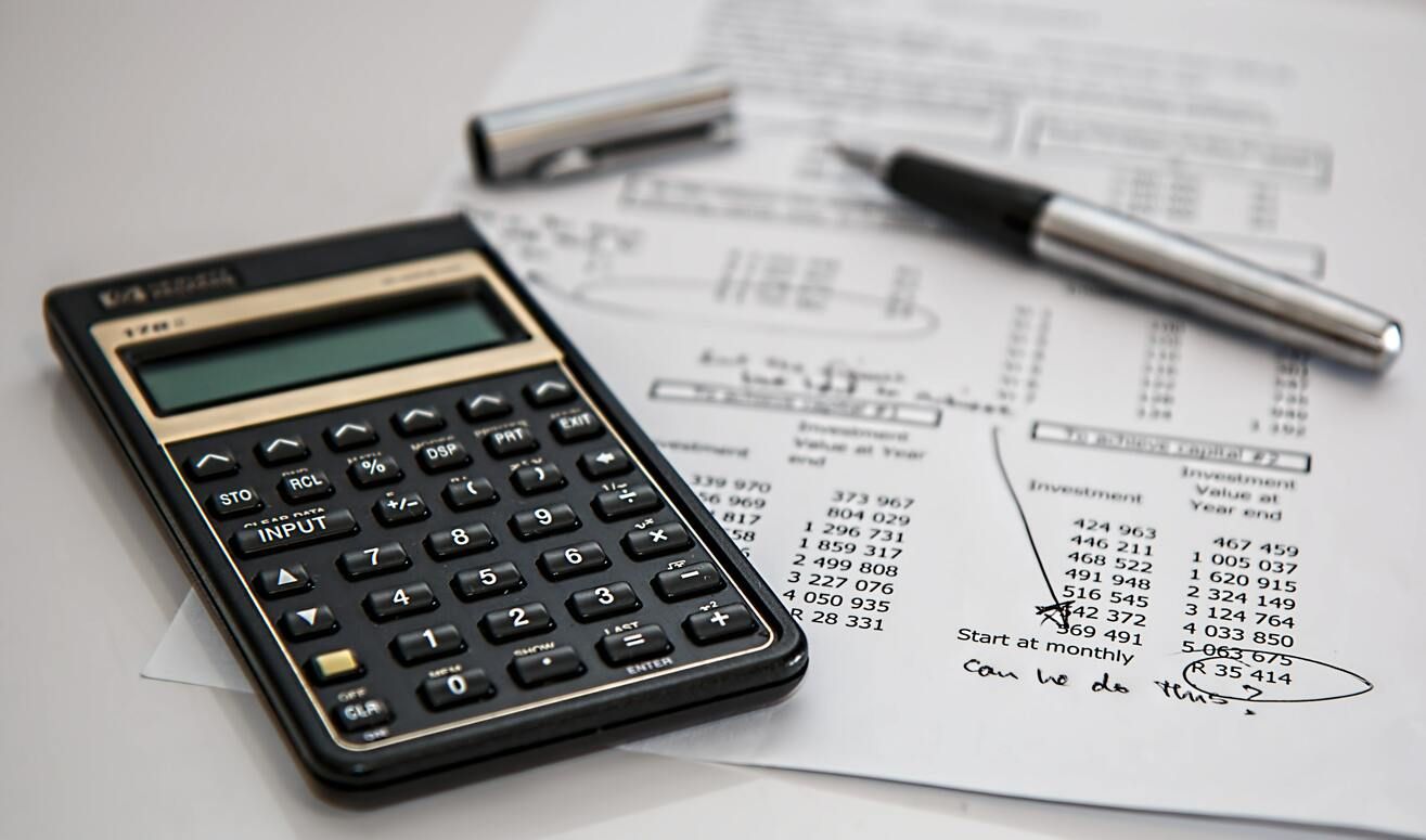Financial statement with calculator and pen used to calculate business finances