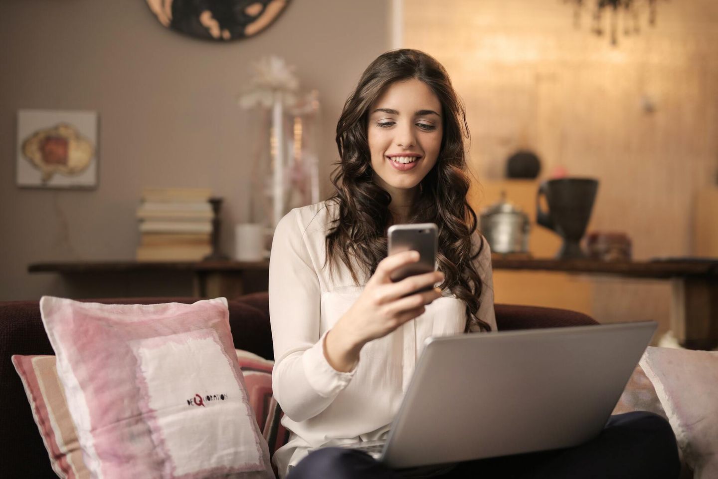 Online business owner sitting on couch with laptop and phone running her business