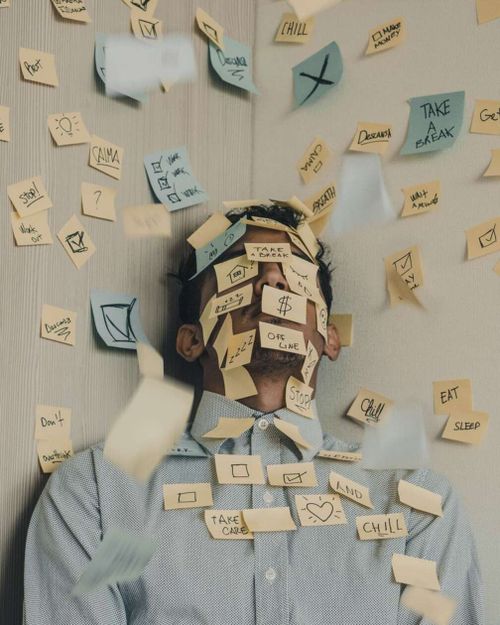 Young man covered in sticky notes who is feeling burned out from work