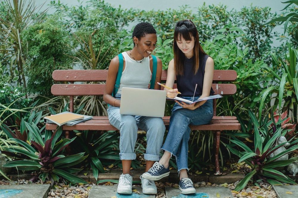 Two freelance women sit on the bench and discus their future mutual content