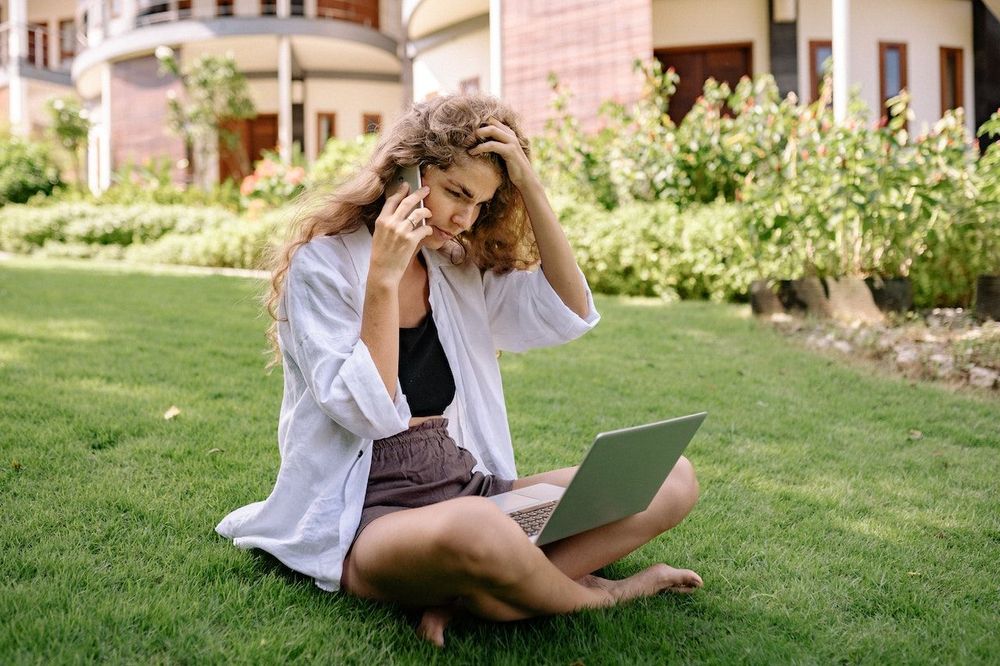 Digital nomad is sitting on the grass and working