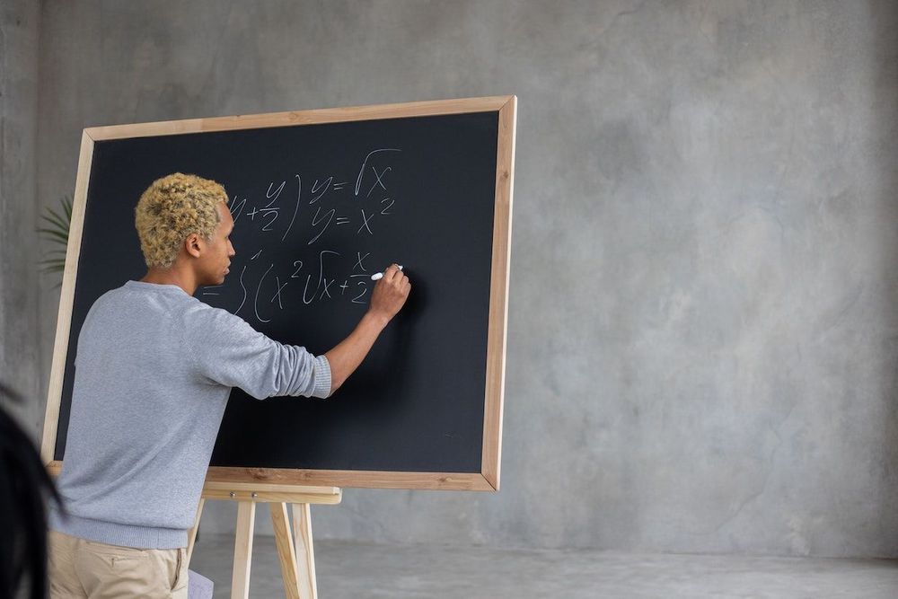 The freelance teacher is writing a formula on the blackboard