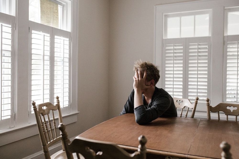 Man is sitting at the table and holding his head with his hand