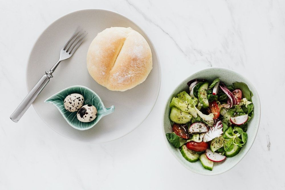 Two plates of healthy salad, eggs and bread