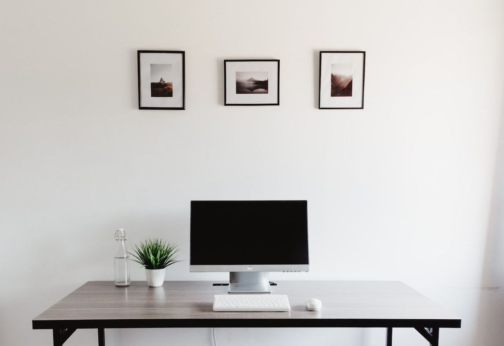 Simple home office with the table, PC, plant and a bottle of water