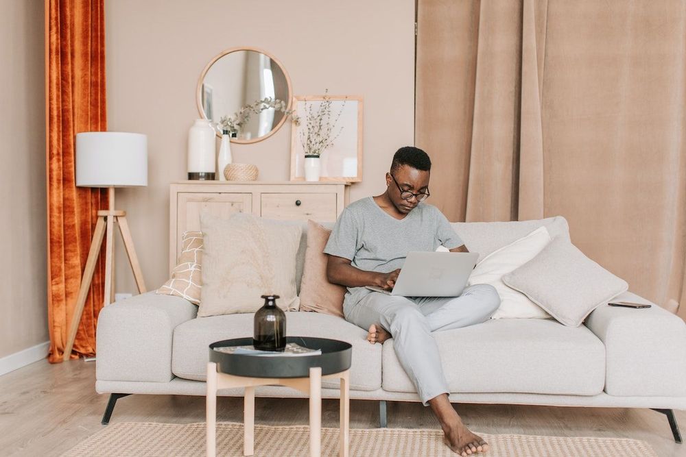 Content creator is sitting on his sofa and working on the SEO strategy with the help of his laptop