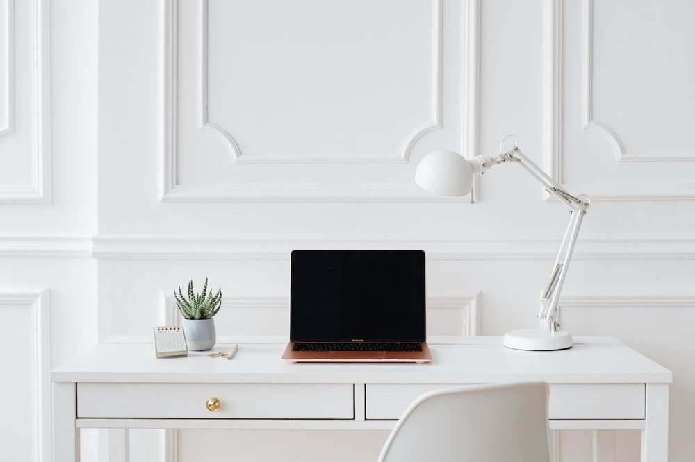 Freelance work space office with the laptop, table, lamp, chair and some plants