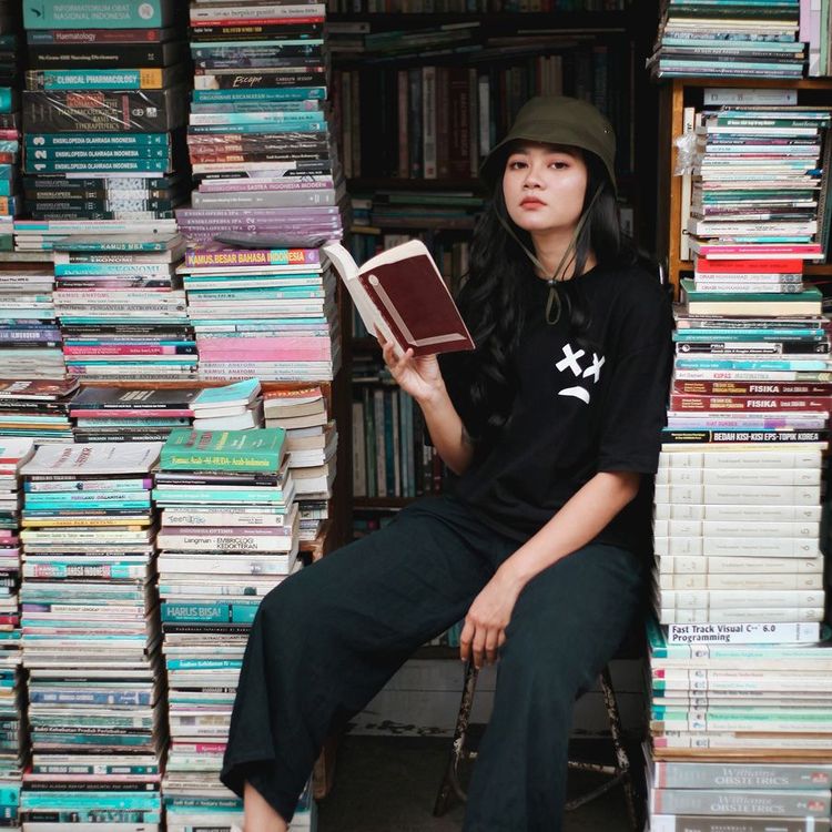 Freelancing sitting on books that she read and help her with her freelance business